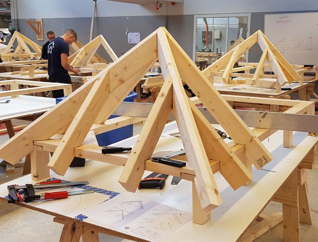 Tømrere bygger trætagspær i et værksted.