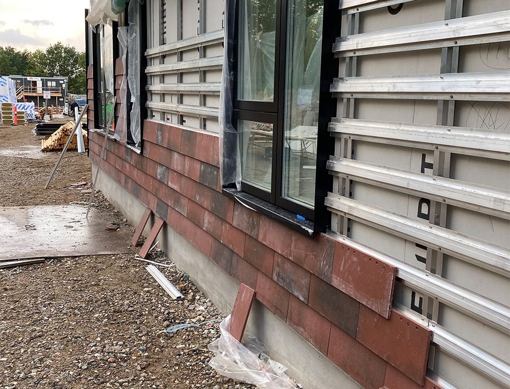 Byggeplads: Ydervæg med rød teglfiner og metalindramning omkring et vindue.