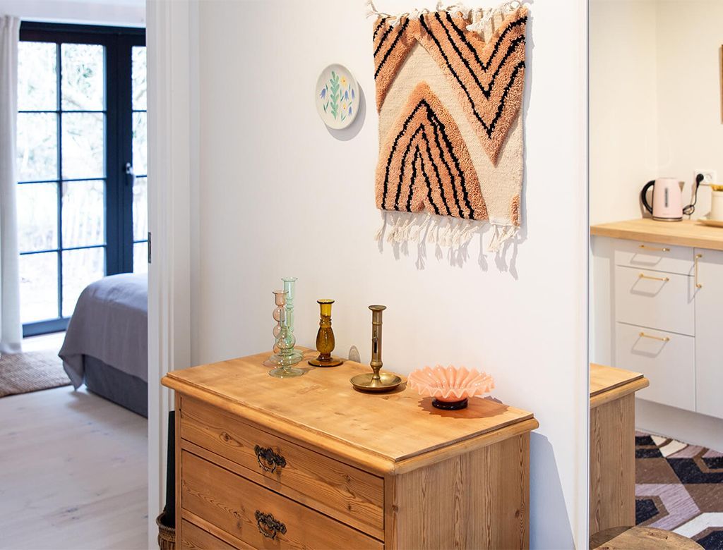 Trækommode med dekorationer, døråbning til soveværelse og tekøkken.