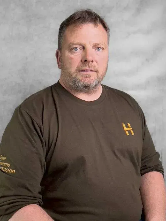 En smilende mand med kort brunt hår iført en mørkegrøn skjorte.