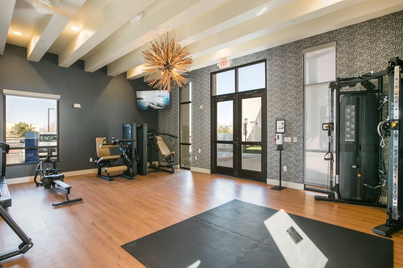 Inside a resident fitness center with cardio and strength machines, a mat, and large windows.