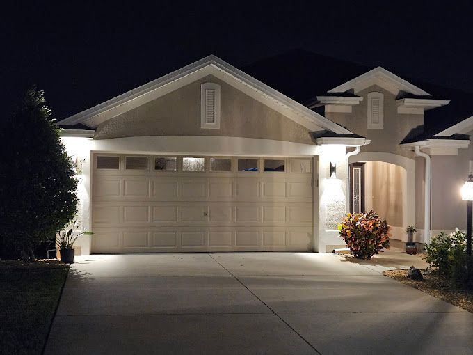 A house with a garage door is lit up at night