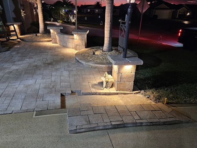 A brick walkway with lights on it and a palm tree in the background