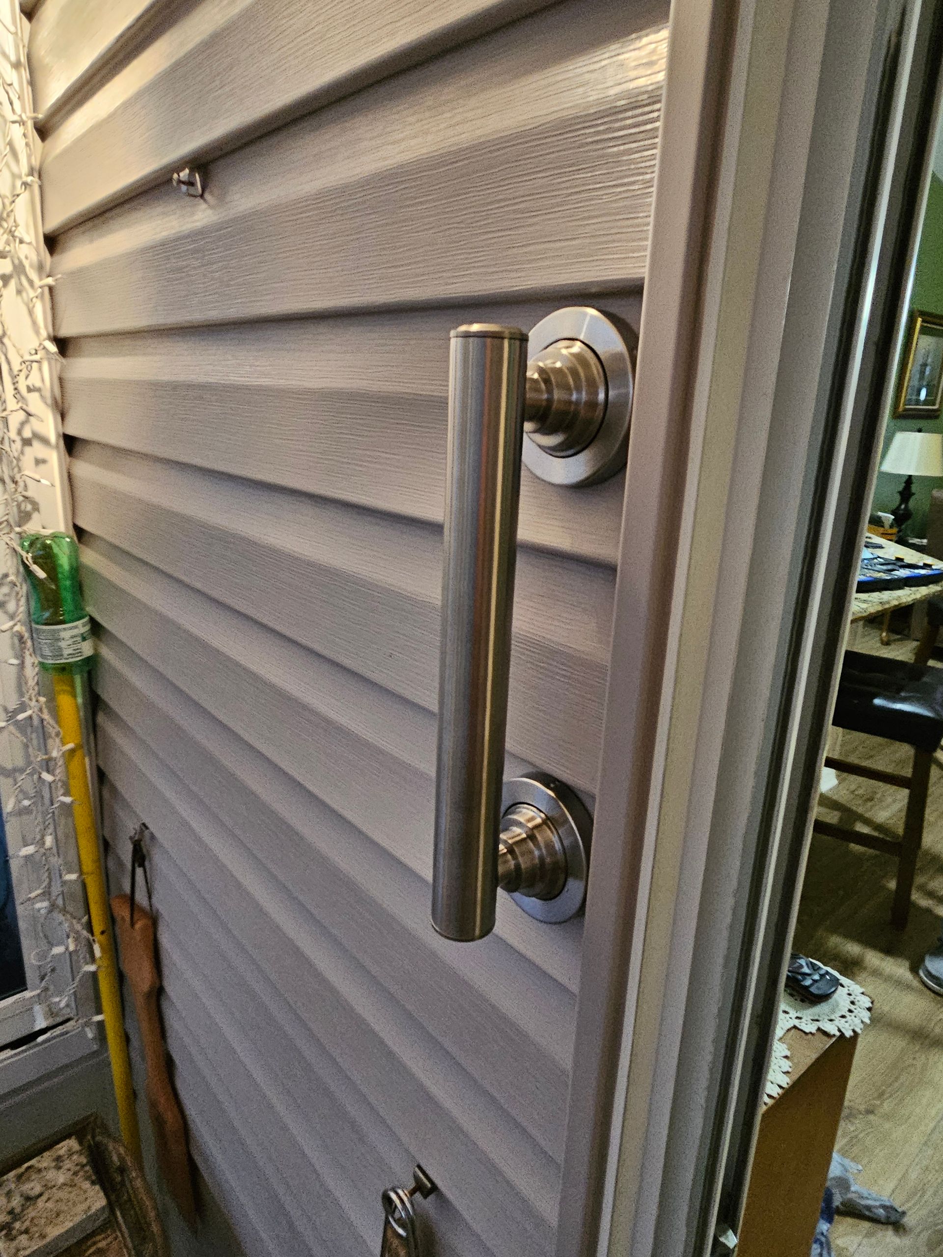 Close-up of a gray door with a vertical silver handle.