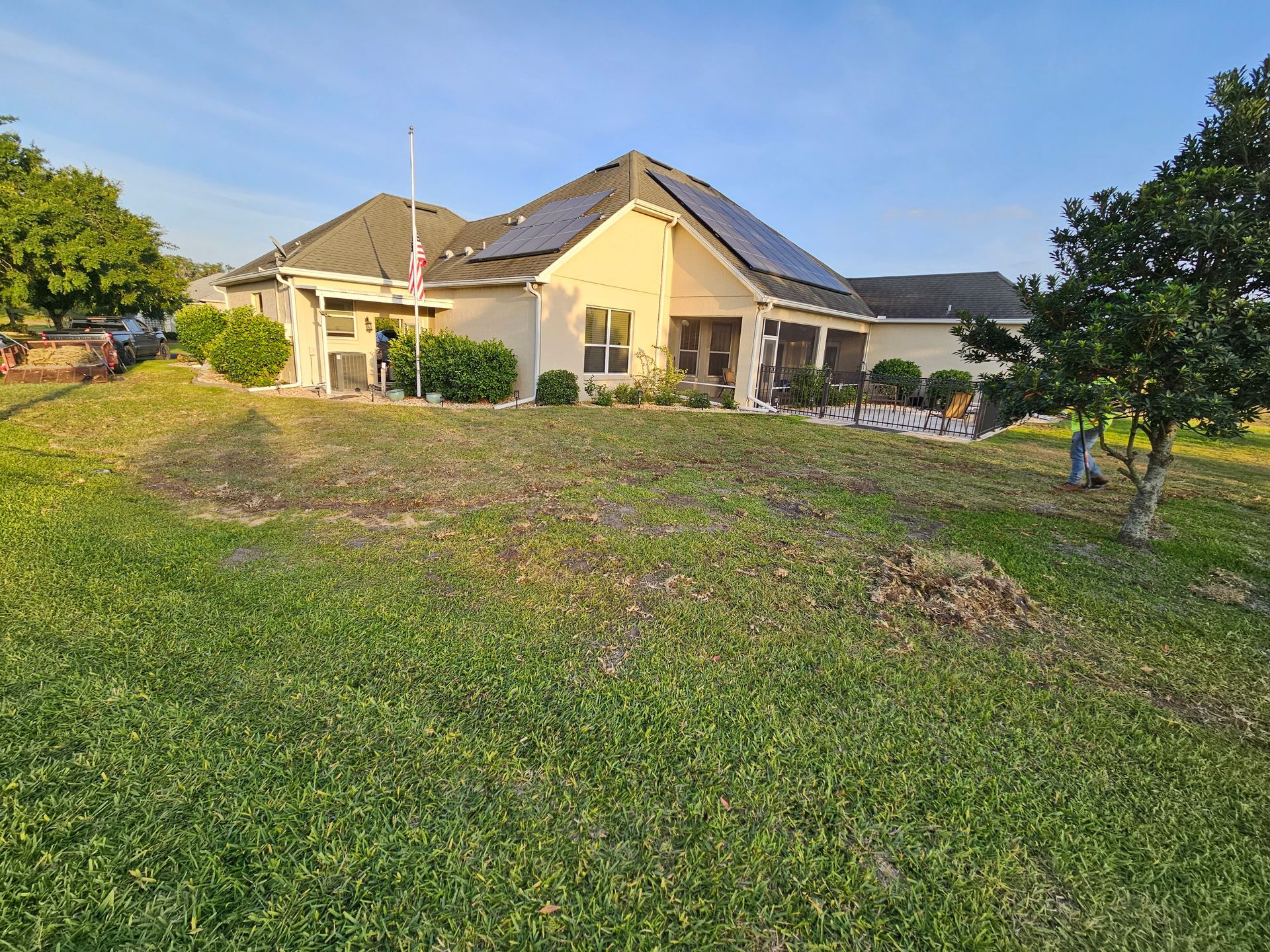 A house with solar panels on the roof, viewed from a grassy yard on a sunny day.
