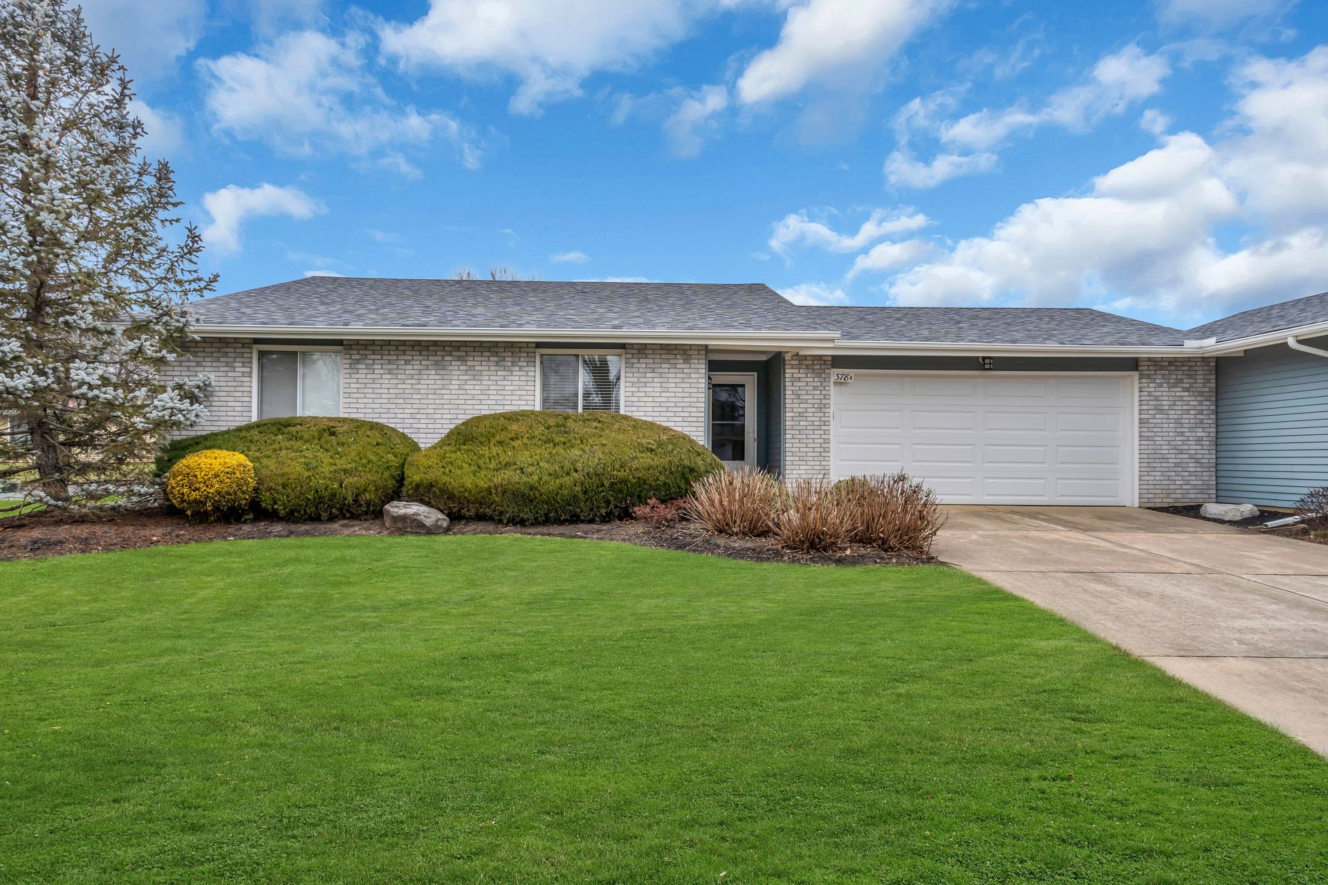 A house with a lush green lawn and a garage door.