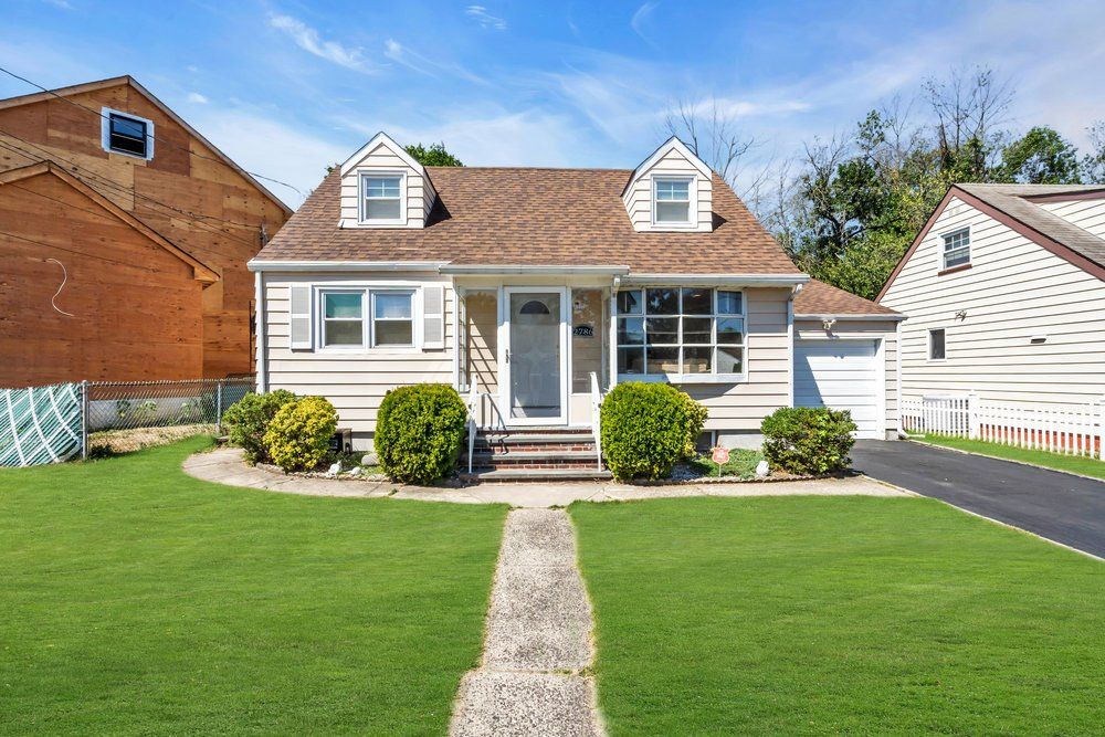A house with a lush green lawn and a walkway leading to it.
