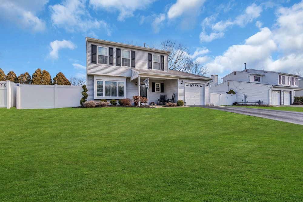 A house with a large lawn in front of it and a white fence.