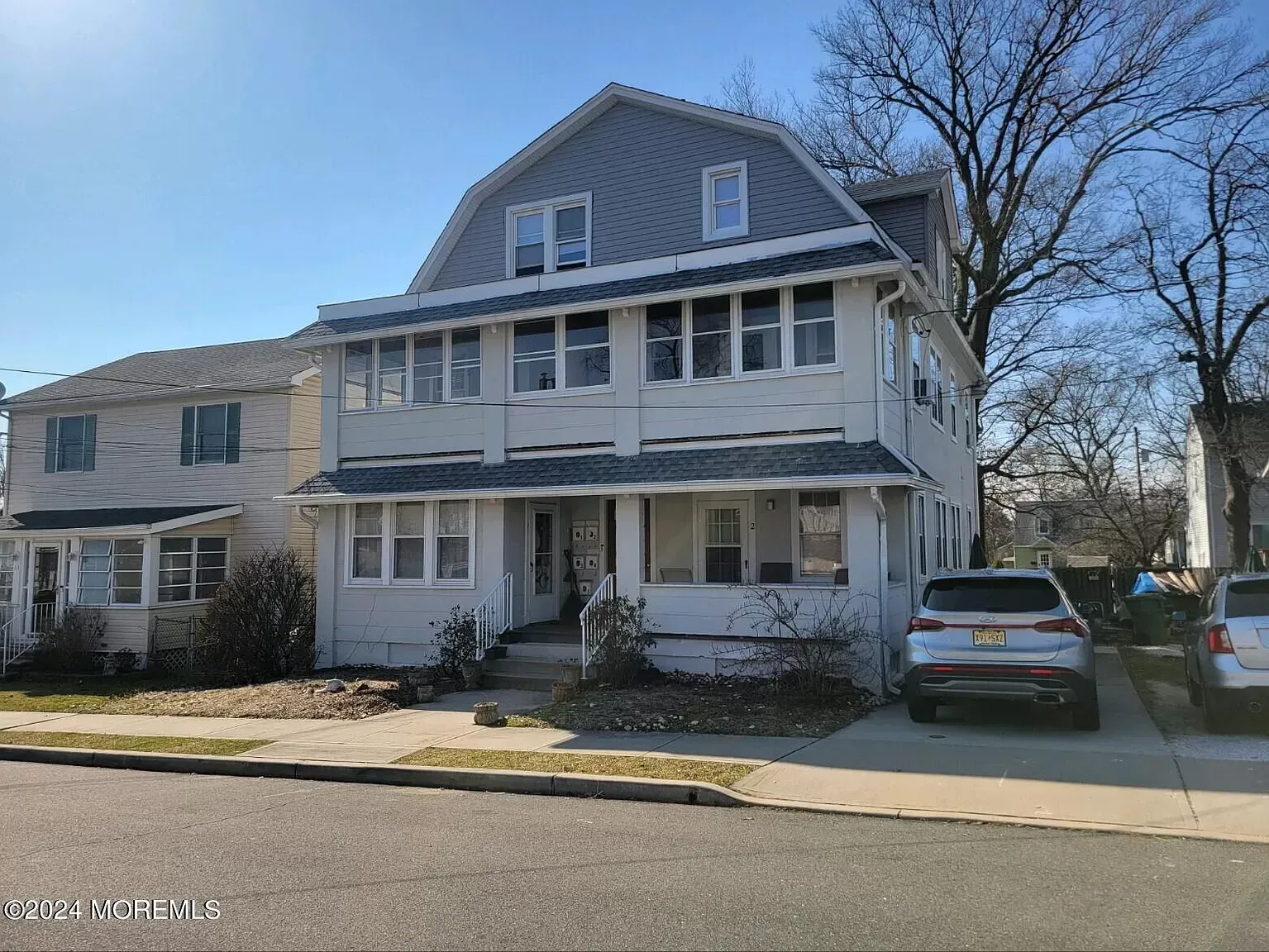 A large white house with a car parked in front of it.