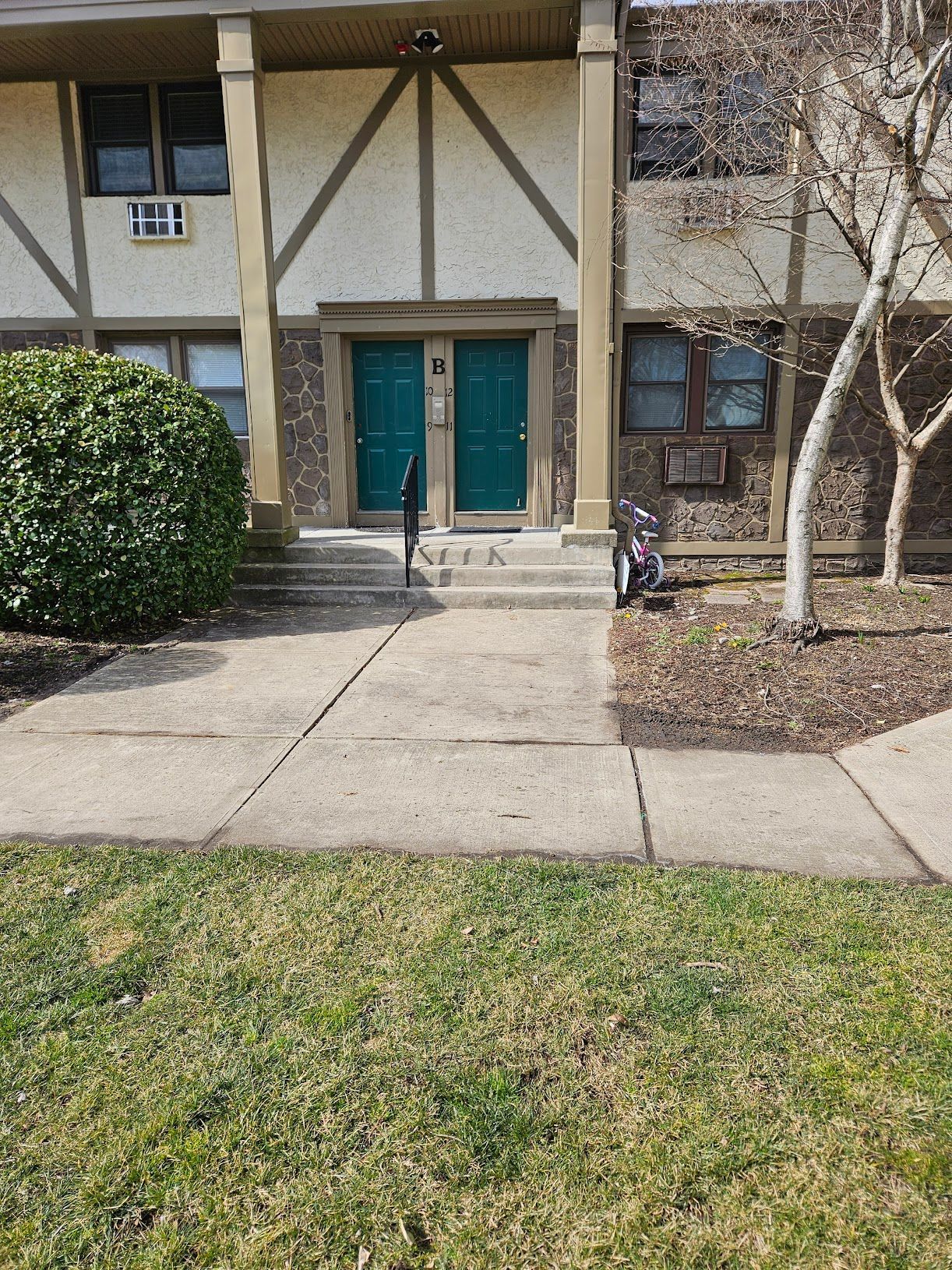 A house with two green doors and a concrete walkway