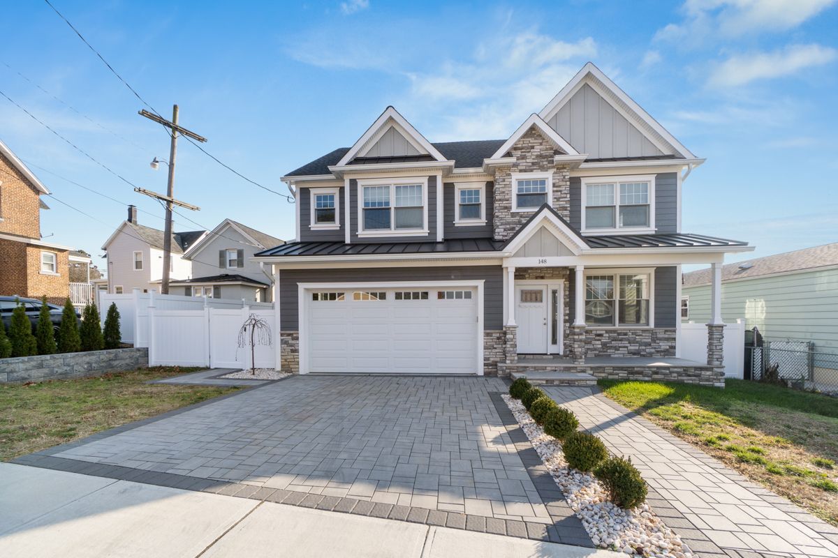 A large house with a white garage door is for sale in a residential area.