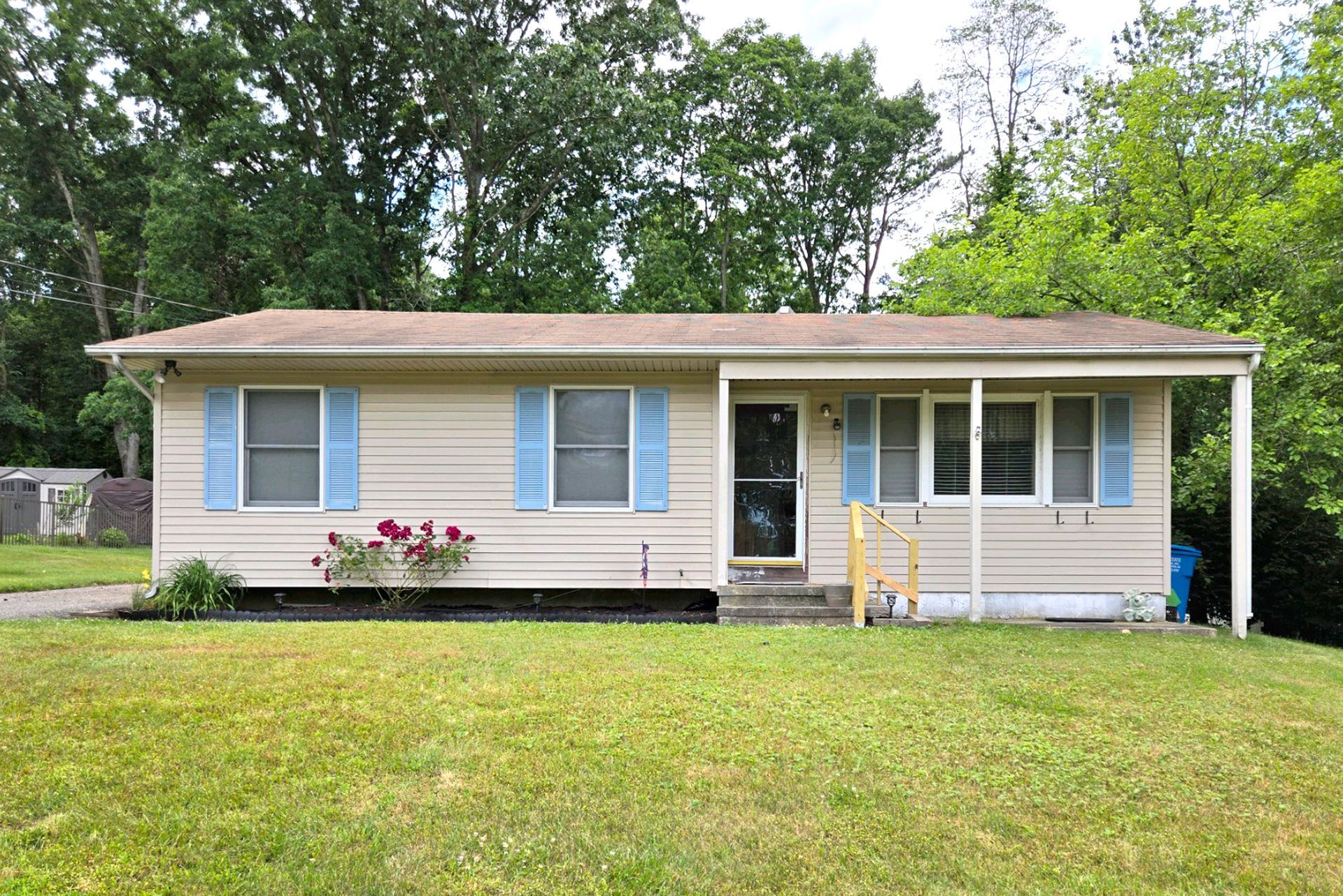 A small house with blue shutters is sitting on top of a lush green lawn.