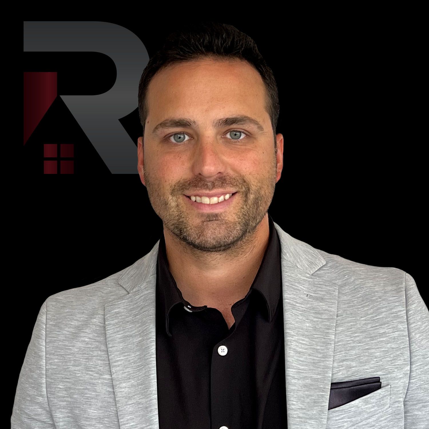 Kris Brus wearing a grey jacket and a black shirt is smiling for the camera.