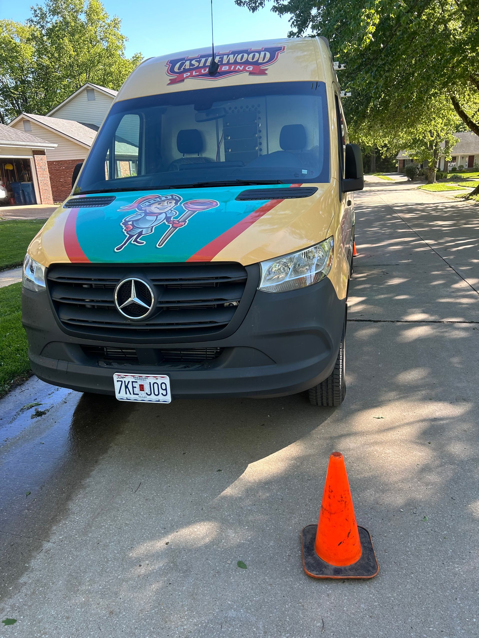 A tan Crazy Wings delivery van parked on a residential street, with an orange traffic cone in front.