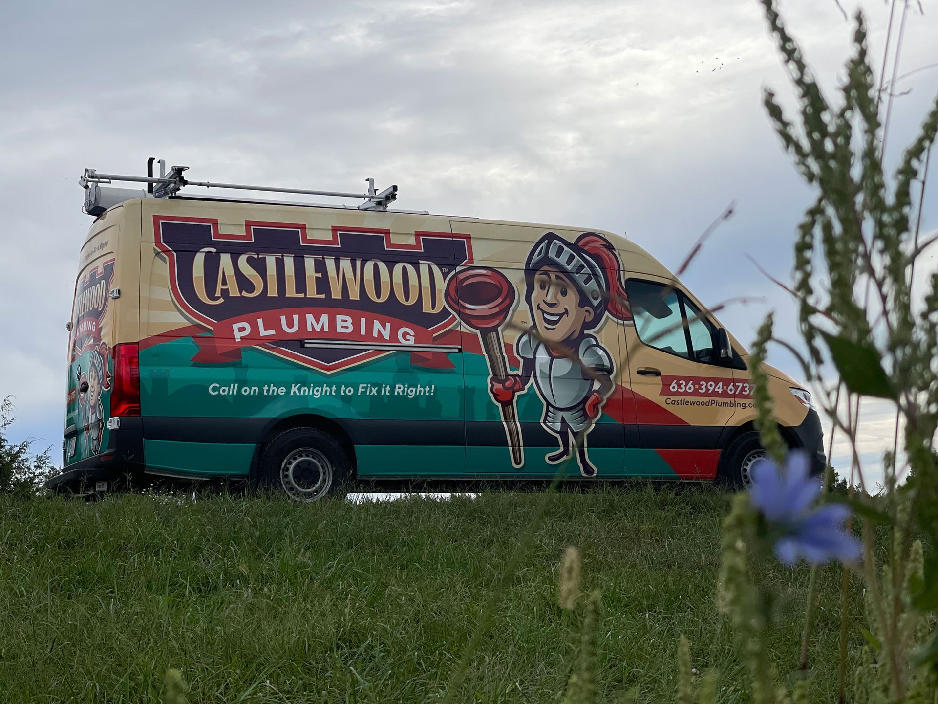 Castlewood Plumbing van with knight mascot on a grassy hill under a cloudy sky.