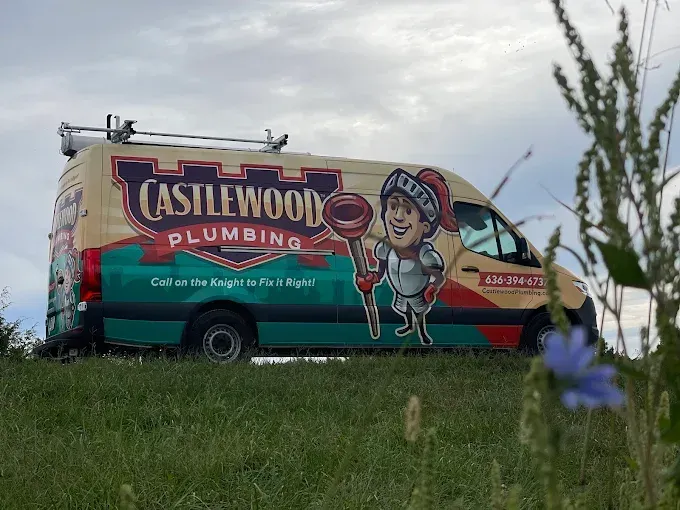 Castlewood Plumbing van with knight mascot parked on a grassy hill.