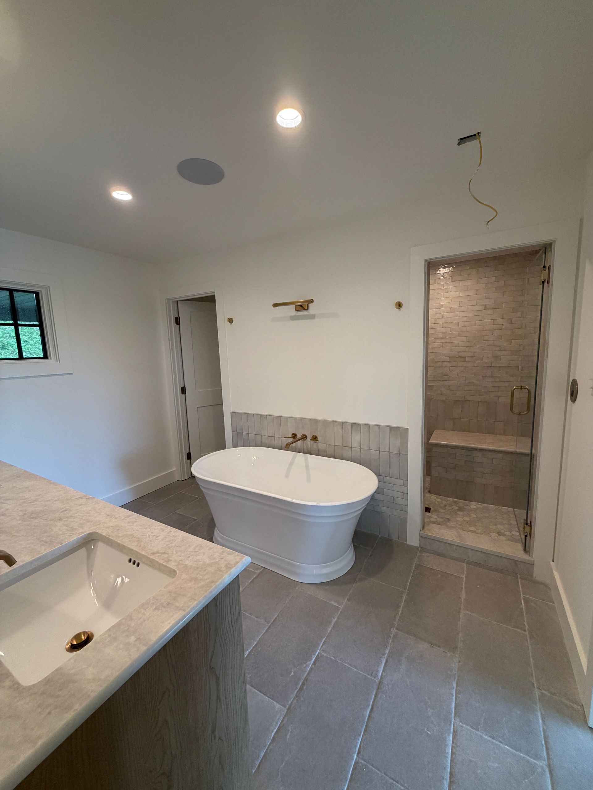 Modern bathroom with freestanding tub, tiled floor, vanity, and walk-in shower.