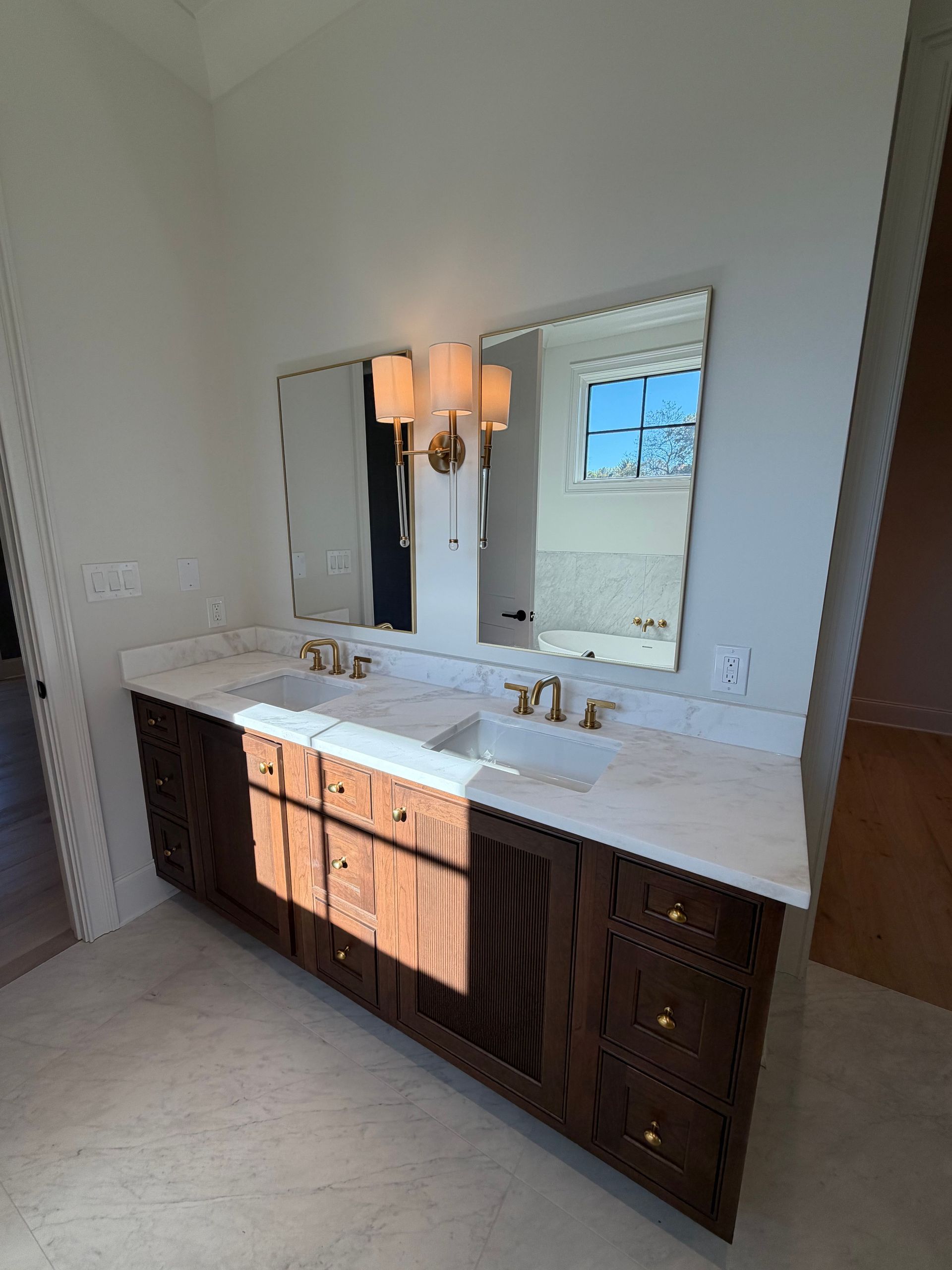 Double vanity bathroom with dark wood cabinets, white countertop, and wall mirror under a light fixture