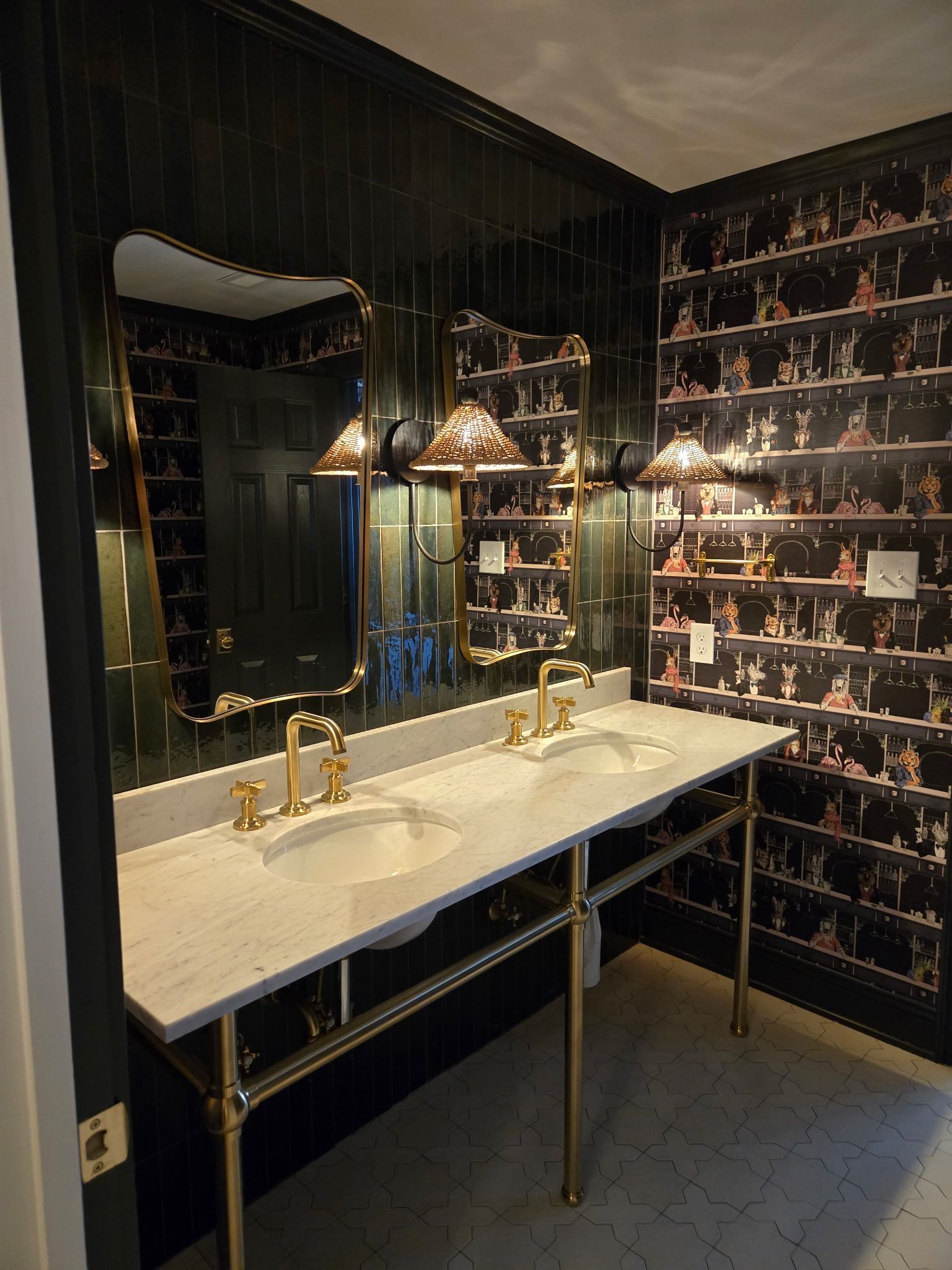 Elegant bathroom vanity with black patterned wallpaper, gold fixtures, and a large mirror.