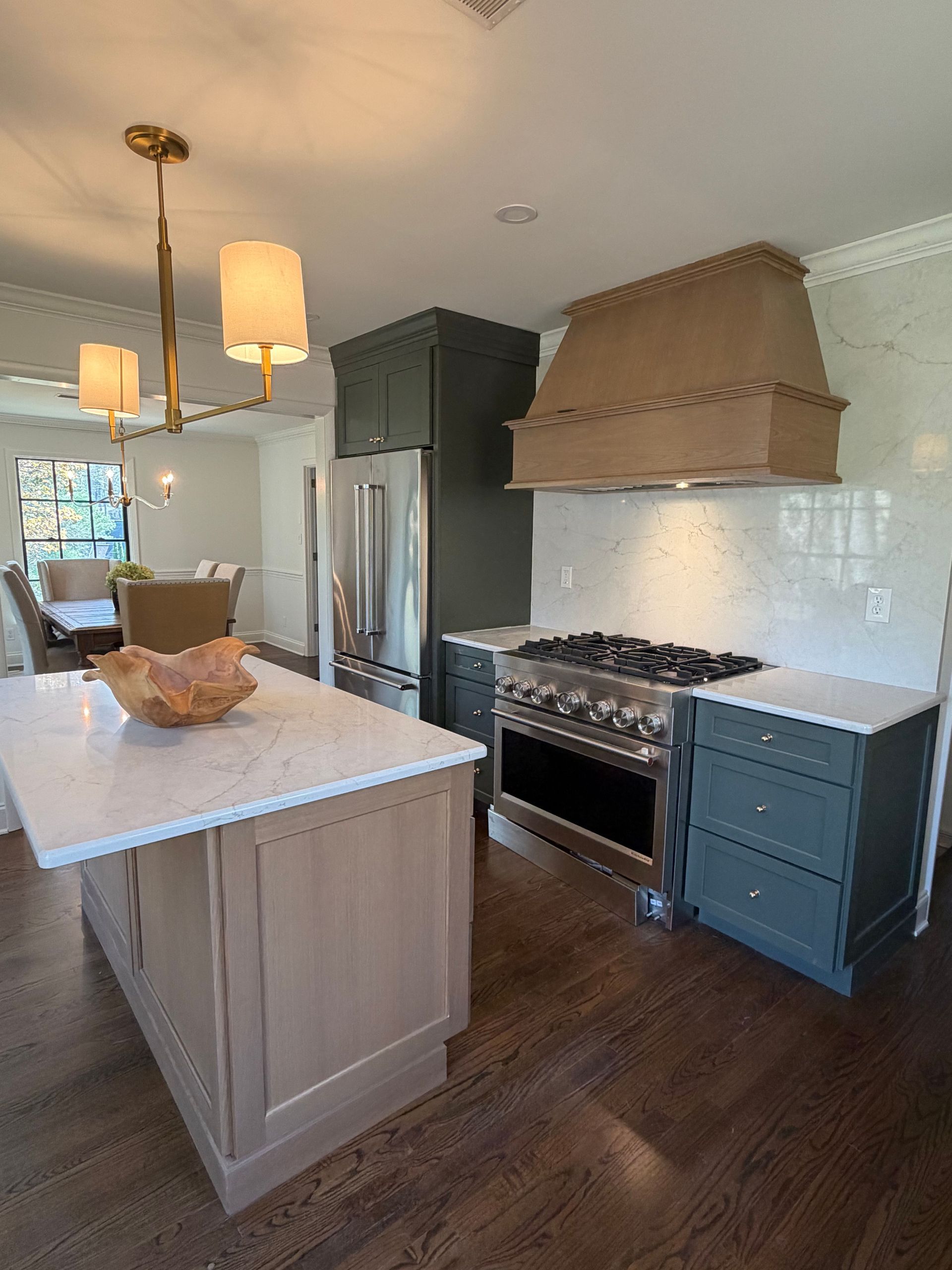Modern kitchen with white island, dark cabinets, gas range, and wood floors
