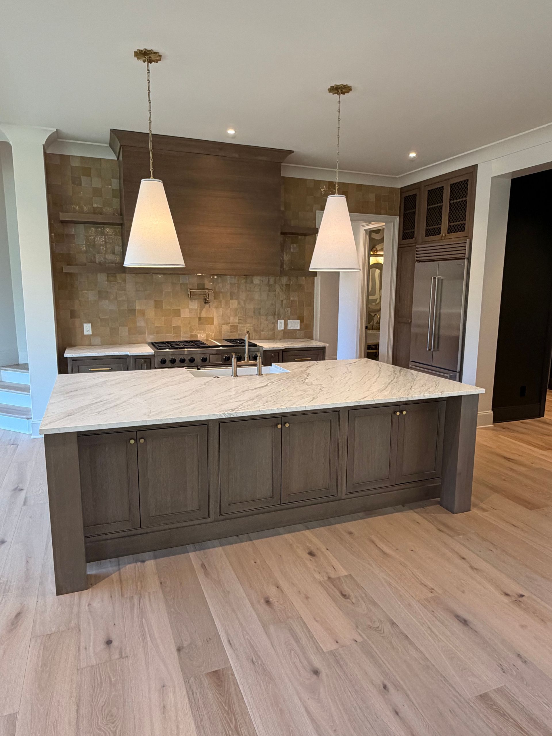 Modern kitchen with dark island, white countertop, pendant lights, and wood flooring