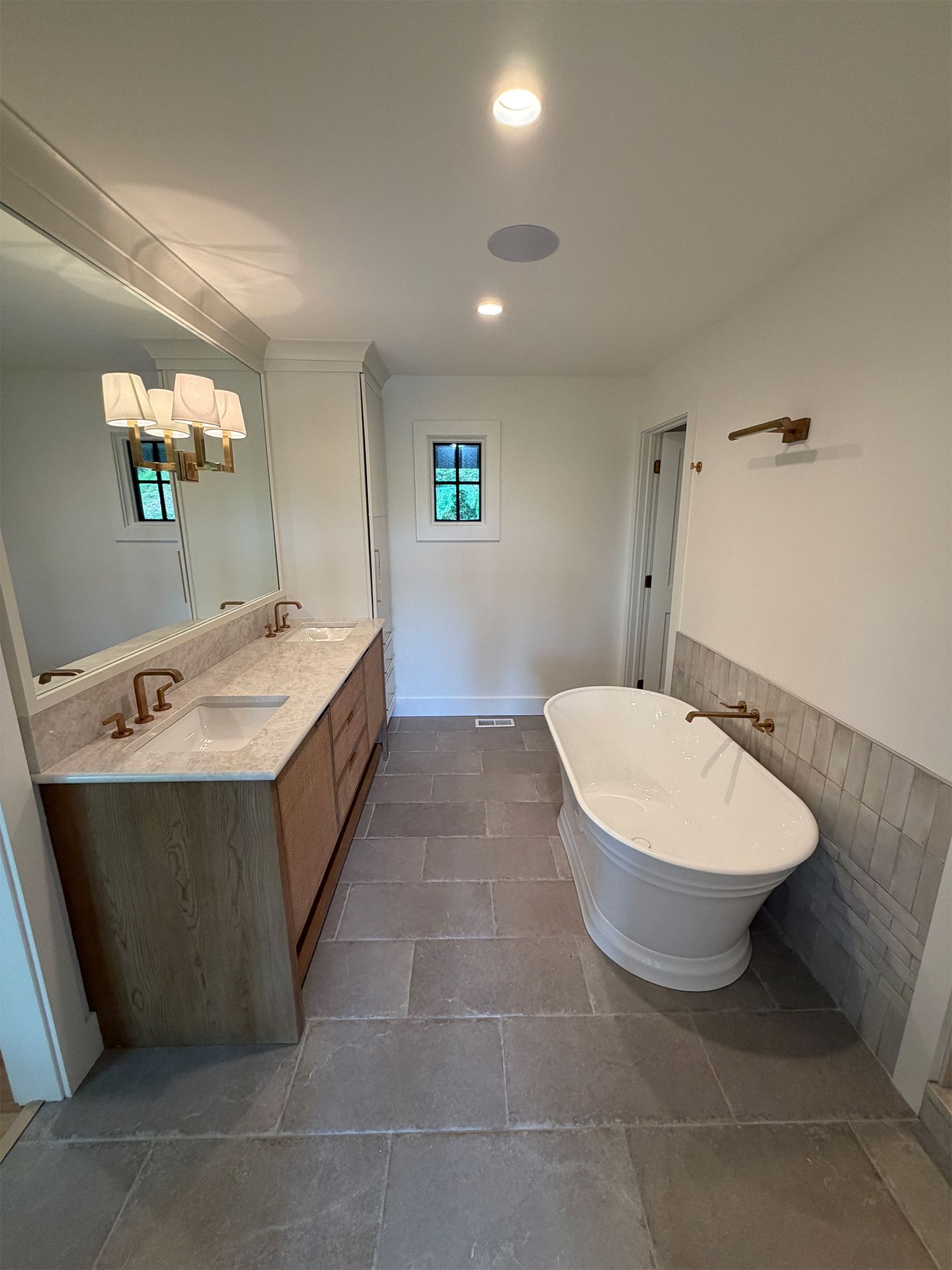 Modern bathroom with freestanding tub, double vanity, gray tile floor, and white walls