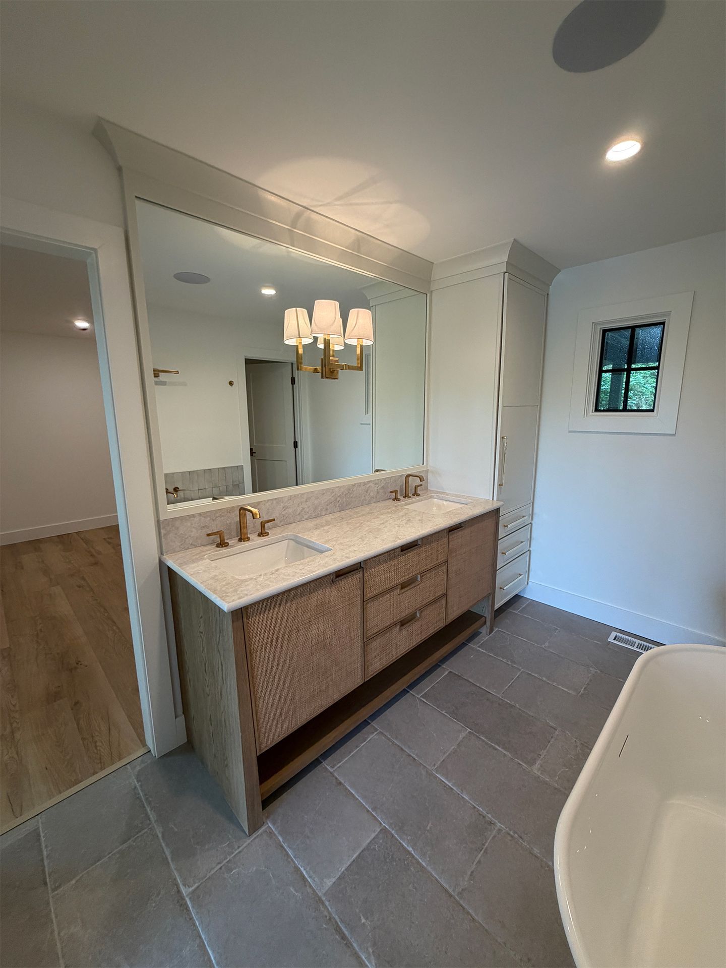Modern bathroom vanity with large mirror, marble countertop, pendant lights, and tiled floor