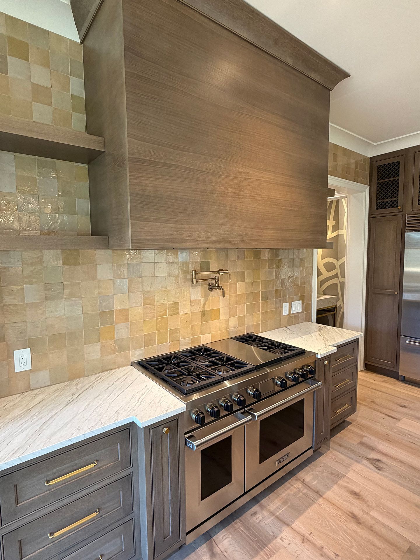 Modern kitchen with wood cabinets, stone tile backsplash, stainless stove, and light countertops