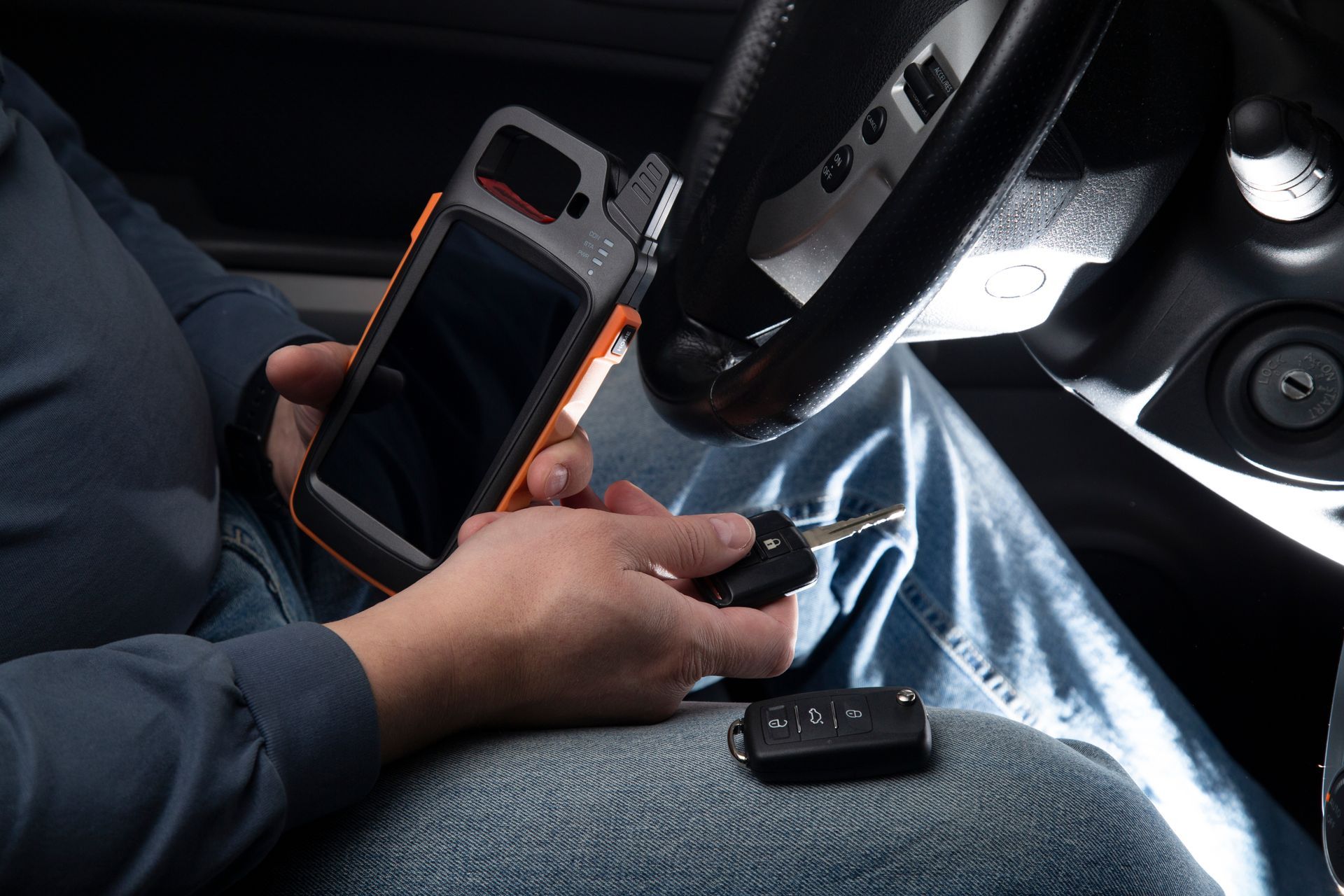 Person inside car using a diagnostic tool with a key and key fob.