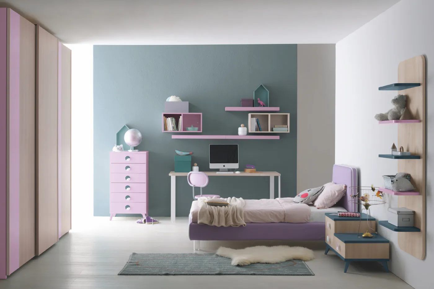 Camera da letto con decorazioni color lavanda e verde acqua, dotata di letto, scrivania, ripiani e cassettiera.