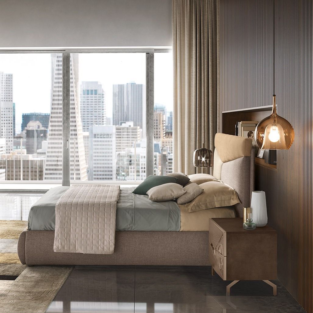 Camera da letto con letto, comodino e finestra con vista sullo skyline della città. Colori neutri.
