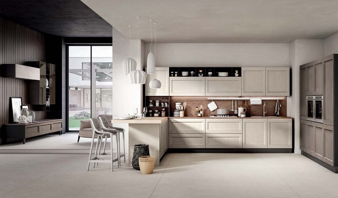 Cucina moderna con mobili in legno chiaro, bancone bar e ampia finestra.