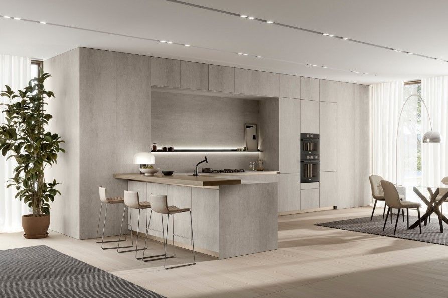 Cucina moderna con finiture in pietra chiara, isola con sgabelli ed elettrodomestici da incasso.