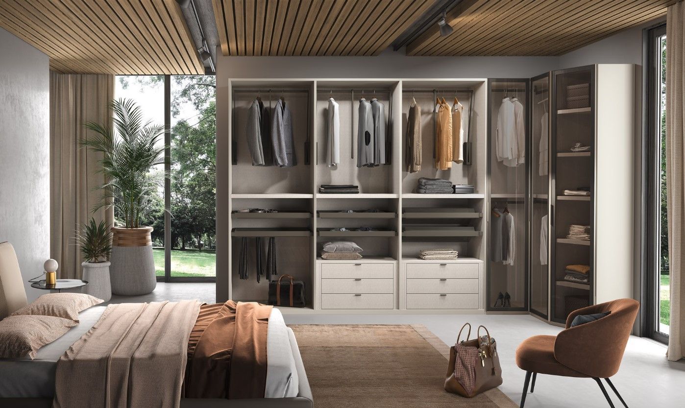 Camera da letto con armadio a muro, colori neutri, letto, sedia e ampie finestre con verde.