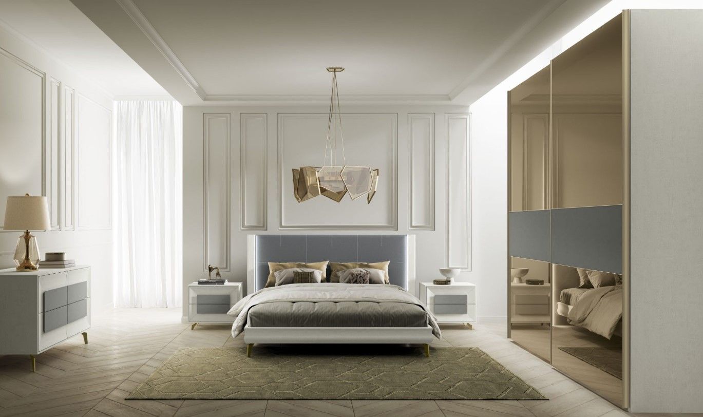 Elegante camera da letto con pareti bianche, letto rivestito in grigio, dettagli dorati e un grande armadio a specchio.