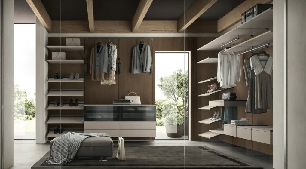 Cabina armadio con ripiani in legno, vestiti e un pouf.