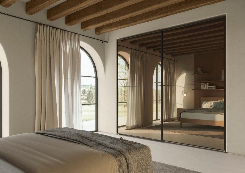 Camera da letto con finestre ad arco, armadio a specchio, travi in ​​legno, toni neutri.