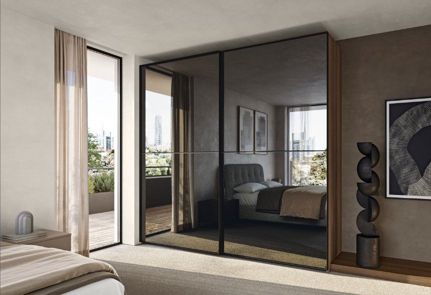 Porte scorrevoli a specchio dell'armadio in una camera da letto con vista sul balcone, che riflettono il letto.