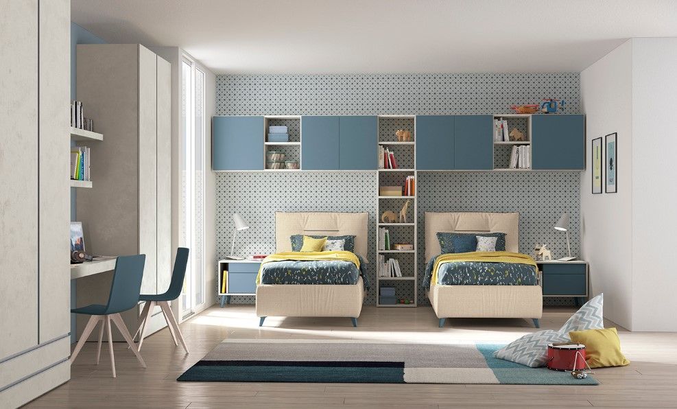 Due letti singoli in una stanza blu e beige. Pensili, scrivanie e dettagli blu.