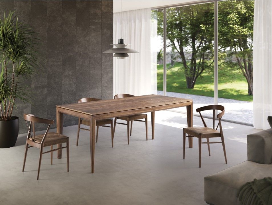 Sala da pranzo con tavolo e sedie in legno, ampia finestra con vista sul giardino.