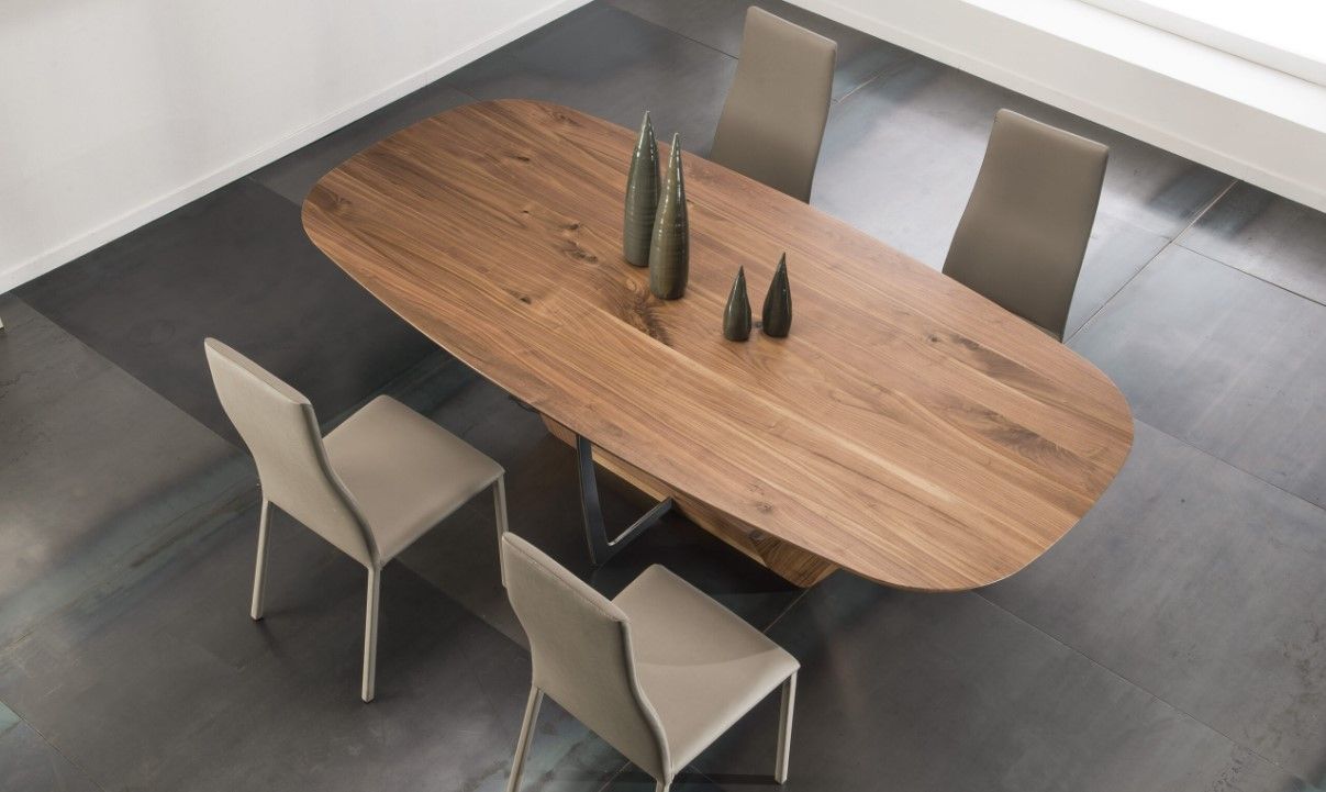 Tavolo da pranzo ovale in legno con quattro sedie e vasi decorativi.