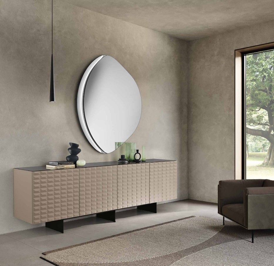 Soggiorno moderno con credenza color cuoio, specchio ovale e poltrona vicino alla finestra.