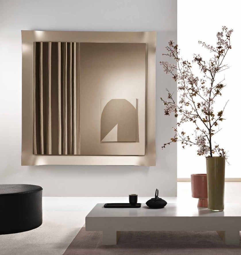 Specchio quadrato con una composizione neutra e astratta sopra un tavolino da caffè bianco con decorazioni e una pianta in vaso.