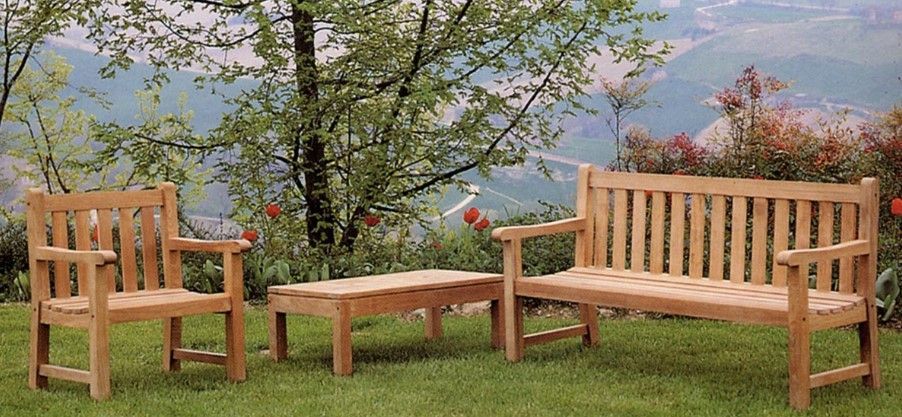 Mobili da esterno in legno disposti su un prato erboso con montagne sullo sfondo.