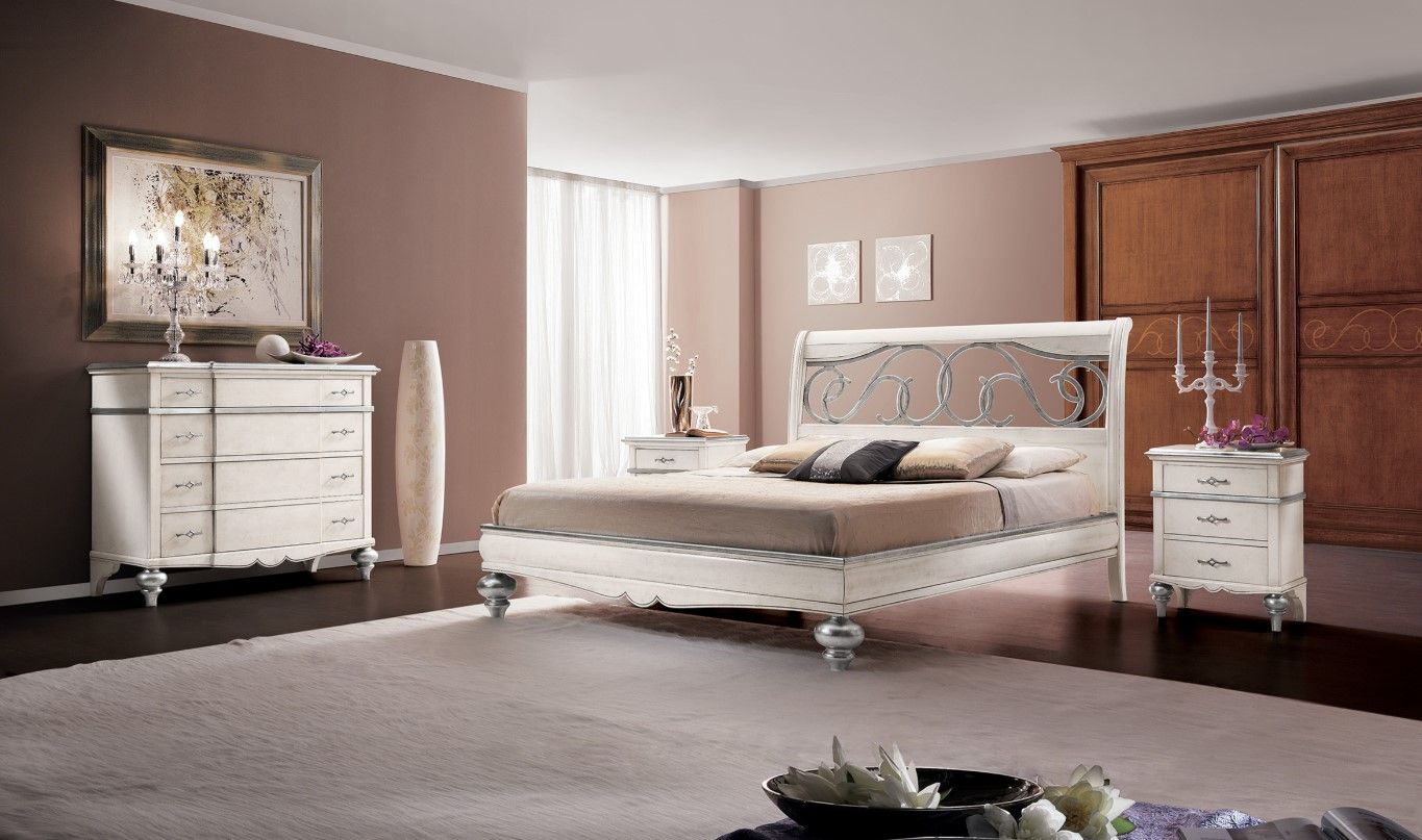 Elegante camera da letto con letto bianco, cassettiera, comodini e armadio in legno scuro, palette di colori neutri.