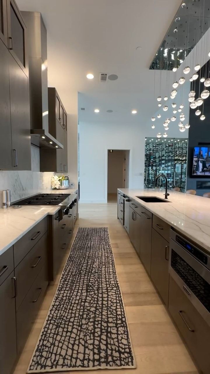 Cucina moderna con mobili grigi, ripiani bianchi e un tappeto a fantasia.