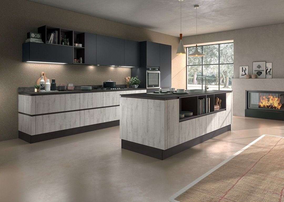 Cucina moderna con mobili grigi e in legno, isola, camino e ampia finestra.