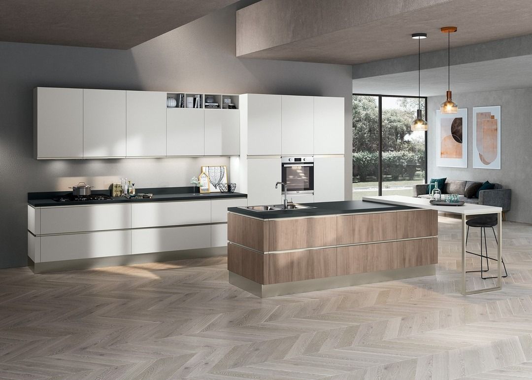 Cucina moderna con mobili bianchi, isola in legno e pareti grigie, con finestra e zona salotto.