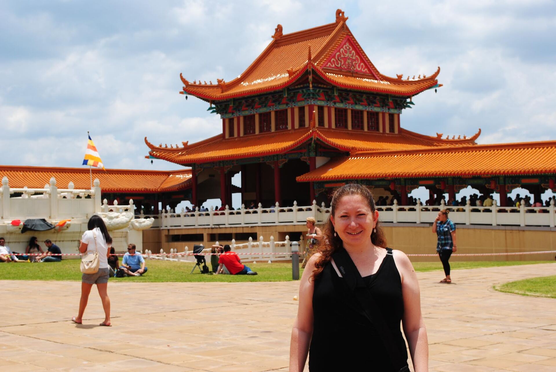 A woman is standing in front of a large chinese building