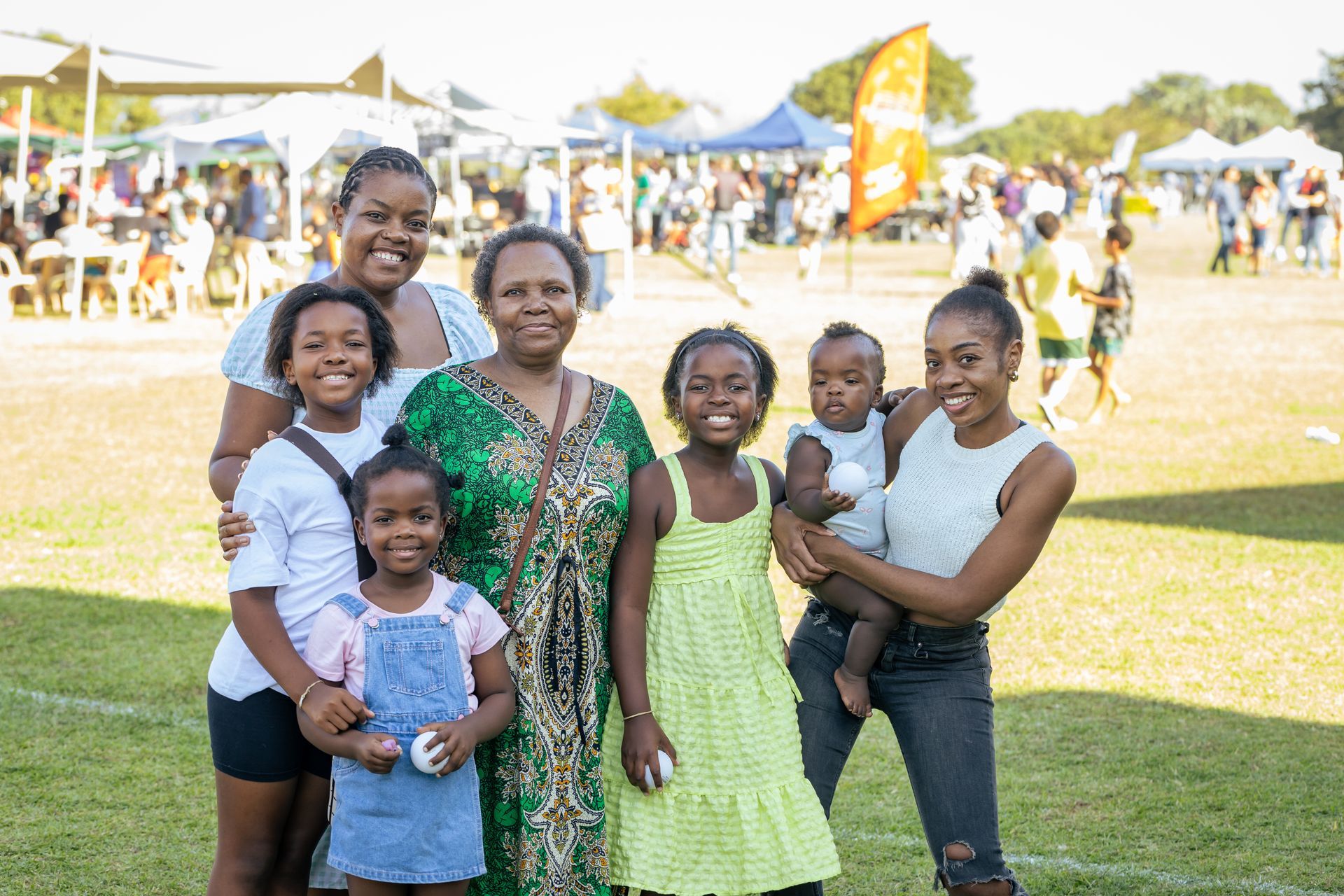 A group of women and children are posing for a picture on a field.